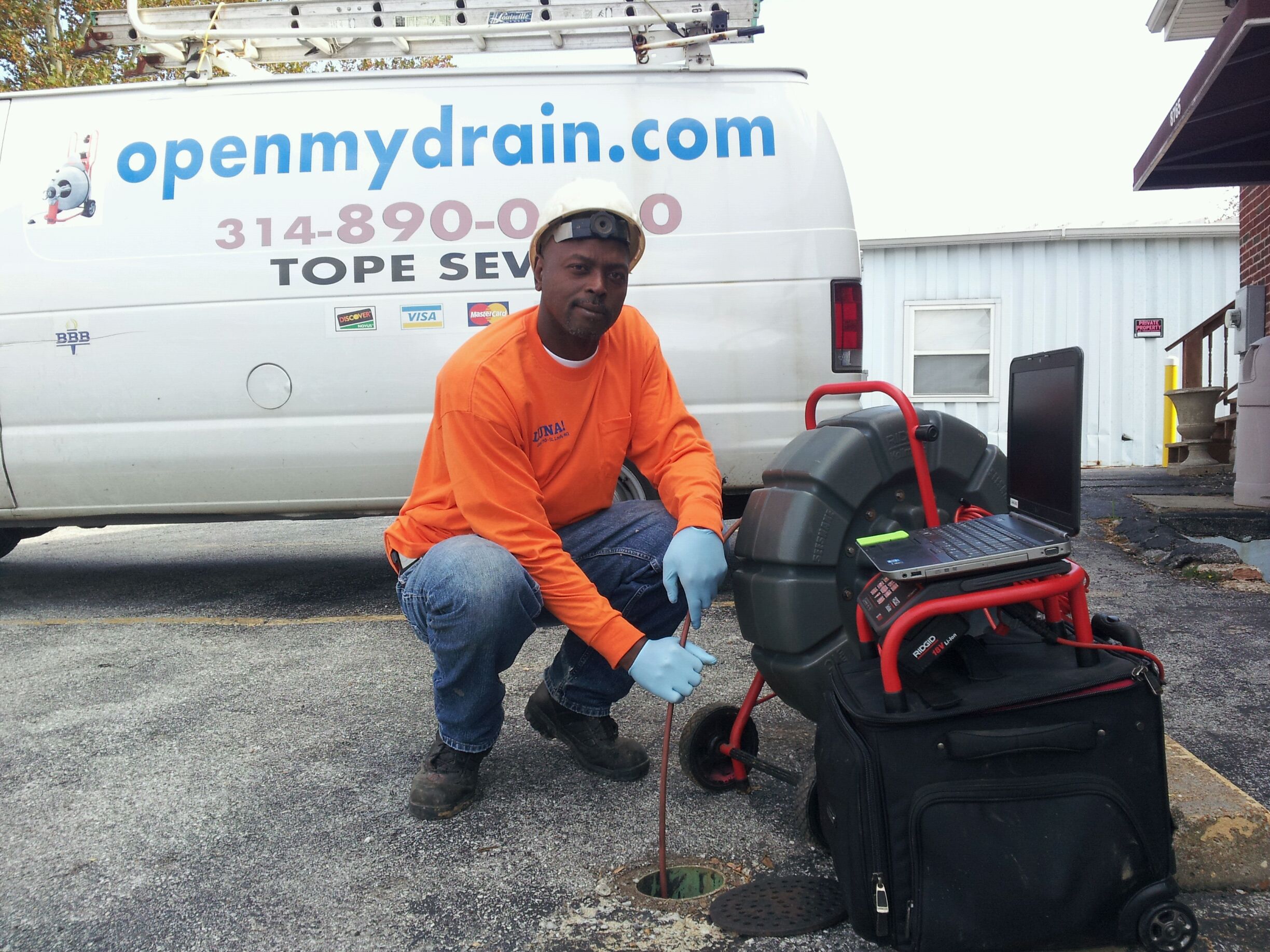 Open My Drain technician running a sewer camera inspection at a cleanout next to the company van in St. Louis